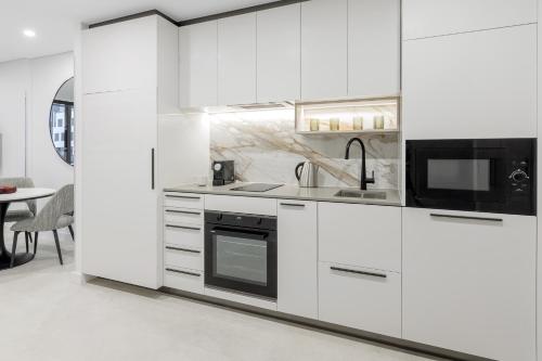 堪培拉Meriton Suites Canberra的白色的厨房配有白色的橱柜和微波炉