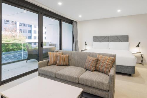 堪培拉Meriton Suites Canberra的一间卧室配有一张床、一张沙发和一张床