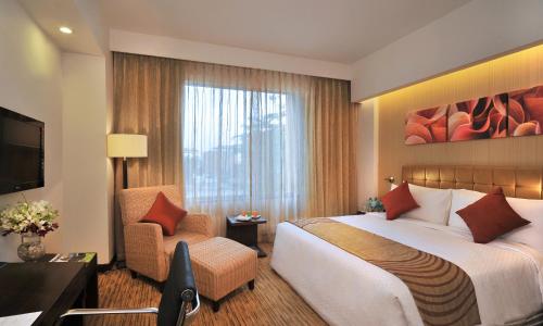 浦那Four Points by Sheraton Hotel and Serviced Apartments Pune的酒店客房带一张大床和一把椅子
