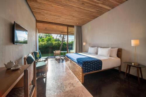 坎古MASMARA Resort Canggu的一间卧室配有一张床、一张书桌和一台电视