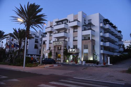 阿加迪尔金沙滩公寓酒店的一座白色的建筑,前面有棕榈树