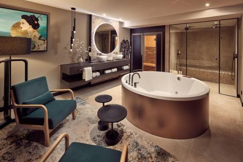 蒂尔蒂尔凡德瓦克酒店的大型浴室设有大浴缸和椅子