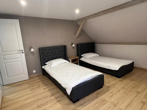 布鲁瓦Gîte « Les Basse des Grouets »的配有2张床的客房,设有门和木地板