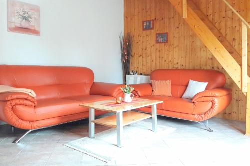 吕本瑙Ferienhaus Herz的两个橙色皮革沙发和一个桌子