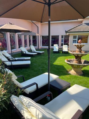 大梅杰尔Spa & Wellness Hotel Orchidea的庭院设有椅子、遮阳伞和喷泉