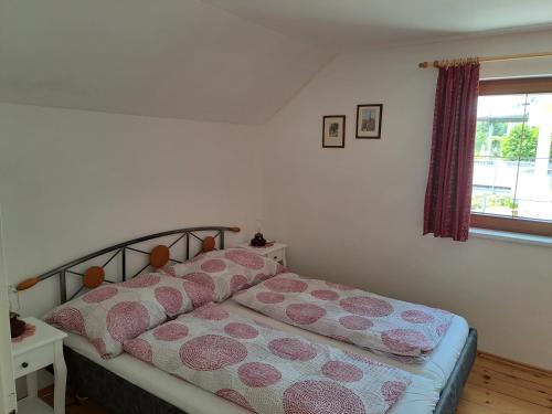 米尔施塔特Ferienhaus Sapplerhof的一间卧室配有带粉红色枕头的床和窗户。