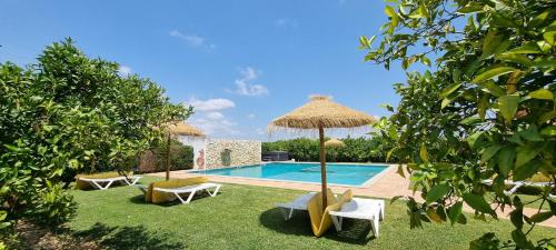 阿尔戈什Quinta dos I's - Algarve的一个带两把椅子和遮阳伞的游泳池
