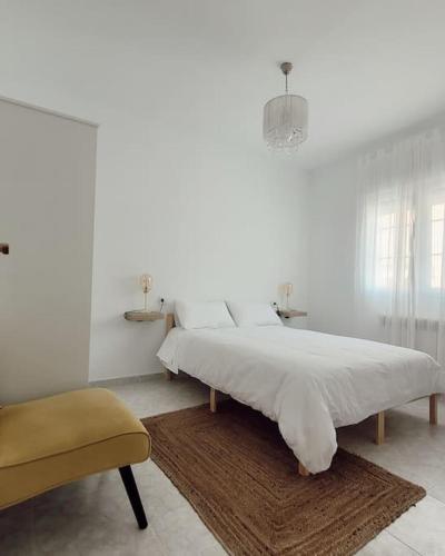 萨莫拉Casa Tonino: Encantadora casa junto al Río Duero的白色卧室配有一张大床和椅子