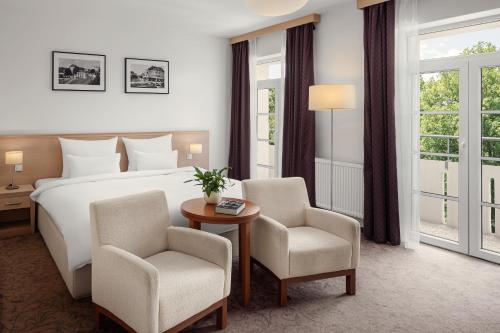 弗兰季谢克矿泉镇Harvey Spa Hotel的酒店客房配有一张床、两把椅子和一张桌子