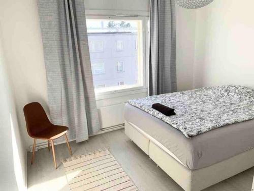 赫尔辛基MELLUNMAKI Renovated 3 bedroom apt next to metro的卧室配有床、椅子和窗户。