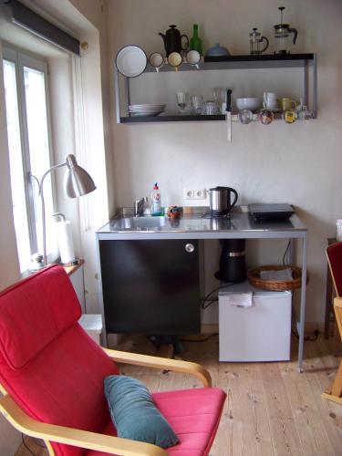 萨斯尼茨Gemütliches kleines Studio in Alt Sassnitz的一间带红色椅子的客厅和一间厨房
