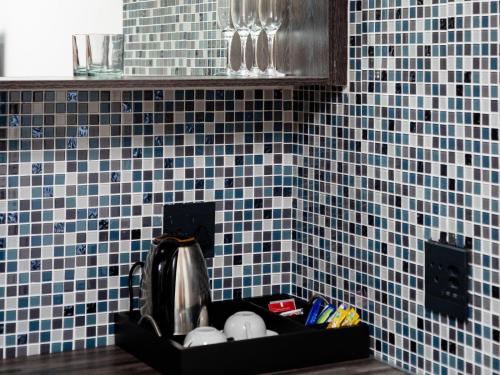 SibasaRoyal Lodge的厨房柜台设有蓝色瓷砖墙壁和水槽