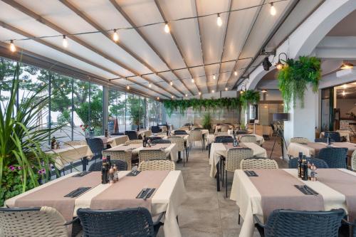 马卡尔斯卡Hotel Central Beach 9的一间设有白色桌椅的餐厅,种植了植物