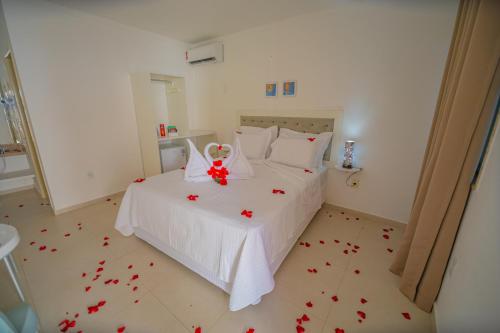 马拉戈日Pousada Polymar的卧室配有白色床,铺有红色玫瑰花瓣。