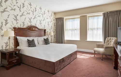 恩尼斯凯里夏山酒店的一间卧室配有一张大床和一把椅子