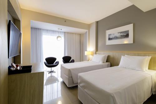 里约热内卢Promenade Link Stay Barra da Tijuca的酒店客房设有两张床和电视。