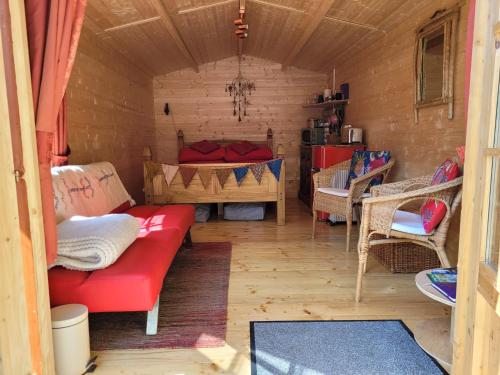 康威Tan y coed's Rosemary Cabin的小房间设有红色的沙发和一张床