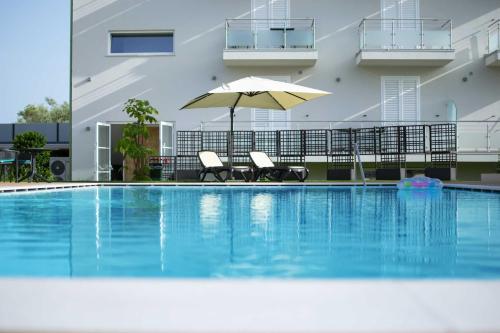 波利卡斯特罗巴森迪诺Resort Policastro的一个带两把椅子和遮阳伞的游泳池