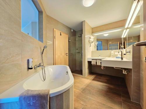 TrebesingFamilienhotel Trebesingerhof的大型浴室设有两个盥洗盆和浴缸。