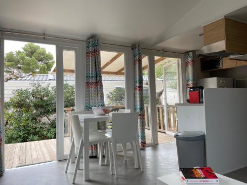 纳博讷Mobil Home - Camping La Falaise的厨房配有白色的桌子和白色的椅子