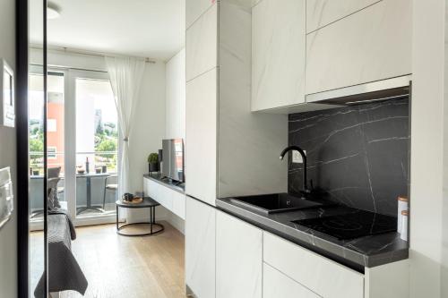 斯普利特Apartman Elena的厨房配有白色橱柜和黑色台面