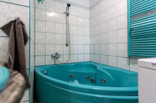 SukoróZsuzsa Apartmanház的带淋浴的瓷砖浴室内的蓝色浴缸