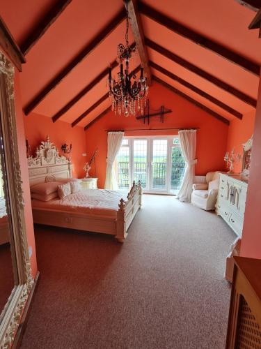 埃尔默顿Barley View的一间卧室设有橙色的墙壁和一张带吊灯的床。