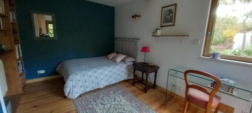 雷恩Chez Anne的一间卧室配有一张床、一张桌子和一个窗户。