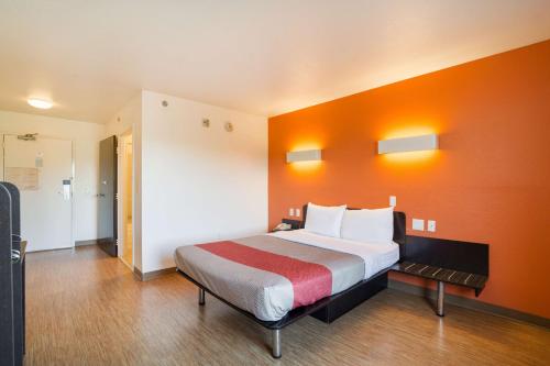 奥古斯塔Motel 6 - Augusta, GA的一间卧室配有一张带橙色墙壁的大床