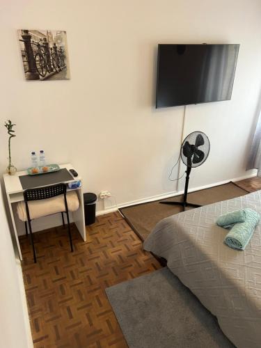 萨卡文Nosso Aconchego的卧室配有1张床、1张书桌和1台平面电视。