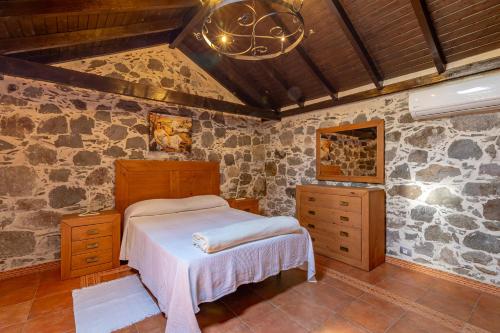 莫甘Casa Los Pinos的一间卧室设有一张床和石墙