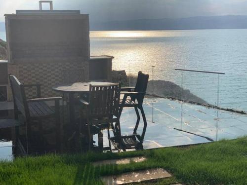 索瓦马Dead Sea Jordan Sea View Samarah Resort Traveler Award 2024 winner的俯瞰水景的天井上的桌椅