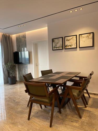 维利波吉Olivea Apartments的一间带木桌和椅子的用餐室