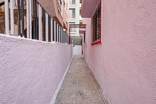 LohogaonOYO Flagship 87488 Hotel Green Breeze的一座狭窄的小巷,在一座建筑旁边设有粉红色的墙壁