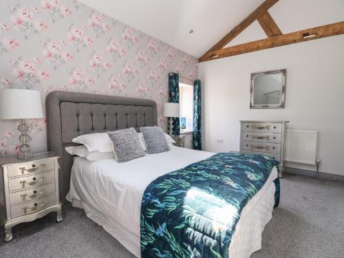 希普利Cunliffe Barn的一间卧室配有一张带花卉壁纸的大床