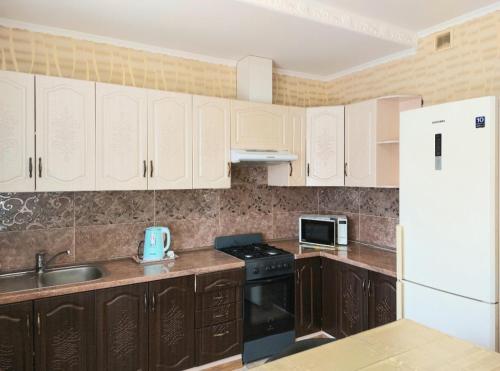 克洛佩夫尼茨基Апартаменты, 2 комн. 6 мест的厨房配有木制橱柜和白色冰箱。