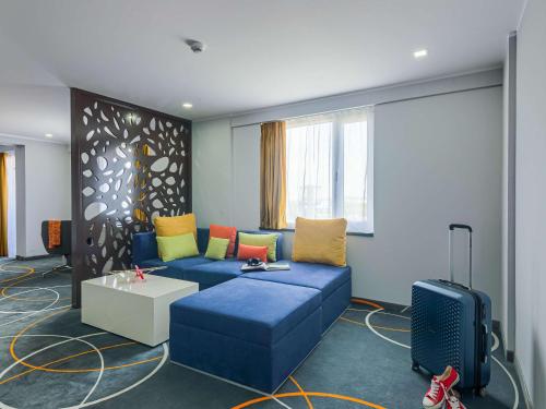 奥托佩尼Ibis Styles Bucharest Airport的客厅配有蓝色沙发及色彩缤纷的枕头