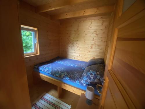 罗日努夫Domekwroznowiepl的木制客房的一张小床,设有窗户
