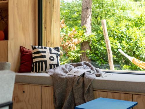 宁斯佩特TED Tiny House的靠窗的座位,带毯子和一本书