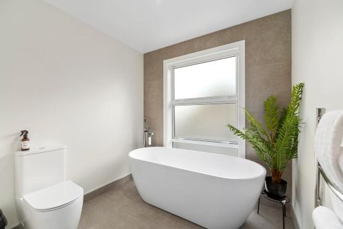 陶波Sanctuary on the Grove的白色的浴室设有卫生间和窗户。