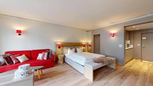 ChampferAbitaziun Europa 302 - Champfèr的一间卧室配有一张床和一张红色的沙发