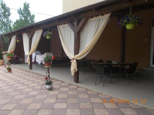 拜勒乌努麦Pensiunea Lari的庭院配有桌椅和白色窗帘
