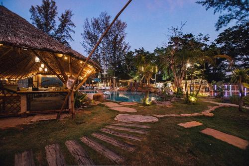 帕克蒙Dugong Village-Green Hotel的夜间带游泳池的度假村