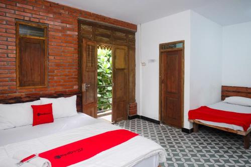马格朗RedDoorz Syariah near Akmil Magelang的一间卧室设有两张床和砖墙