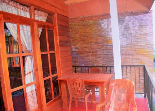 埃拉Green cottage Ella的阳台的门廊配有木桌和椅子