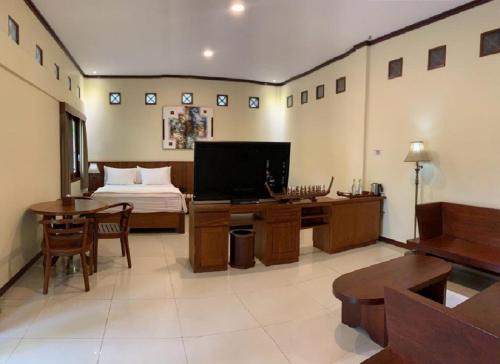 Hotel & Villa Bukit Indah Saumlaki by LeGreen的一间卧室配有一张床和一张书桌及电视