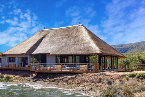 阿多Barefoot Addo Elephant Lodge的海滩上带茅草屋顶的房子