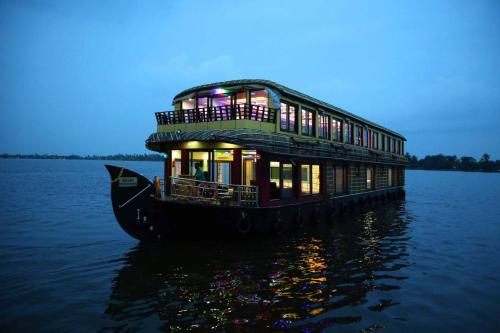 阿勒皮Meghavarsham Luxury cruise的船屋在夜间漂浮在水面上