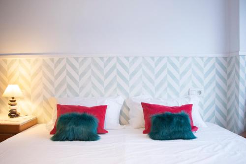 圣地亚哥－德孔波斯特拉Luxury Singular Apartments的卧室配有白色的床和红色及绿色枕头