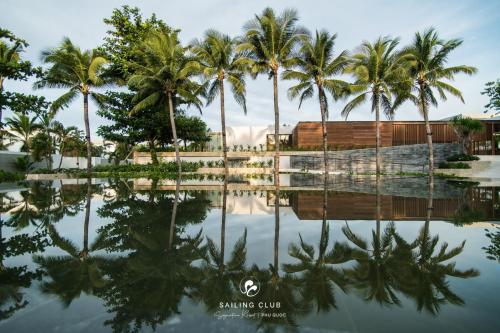富国Sailing Club Signature Resort Phu Quoc的度假村水中棕榈树的反射